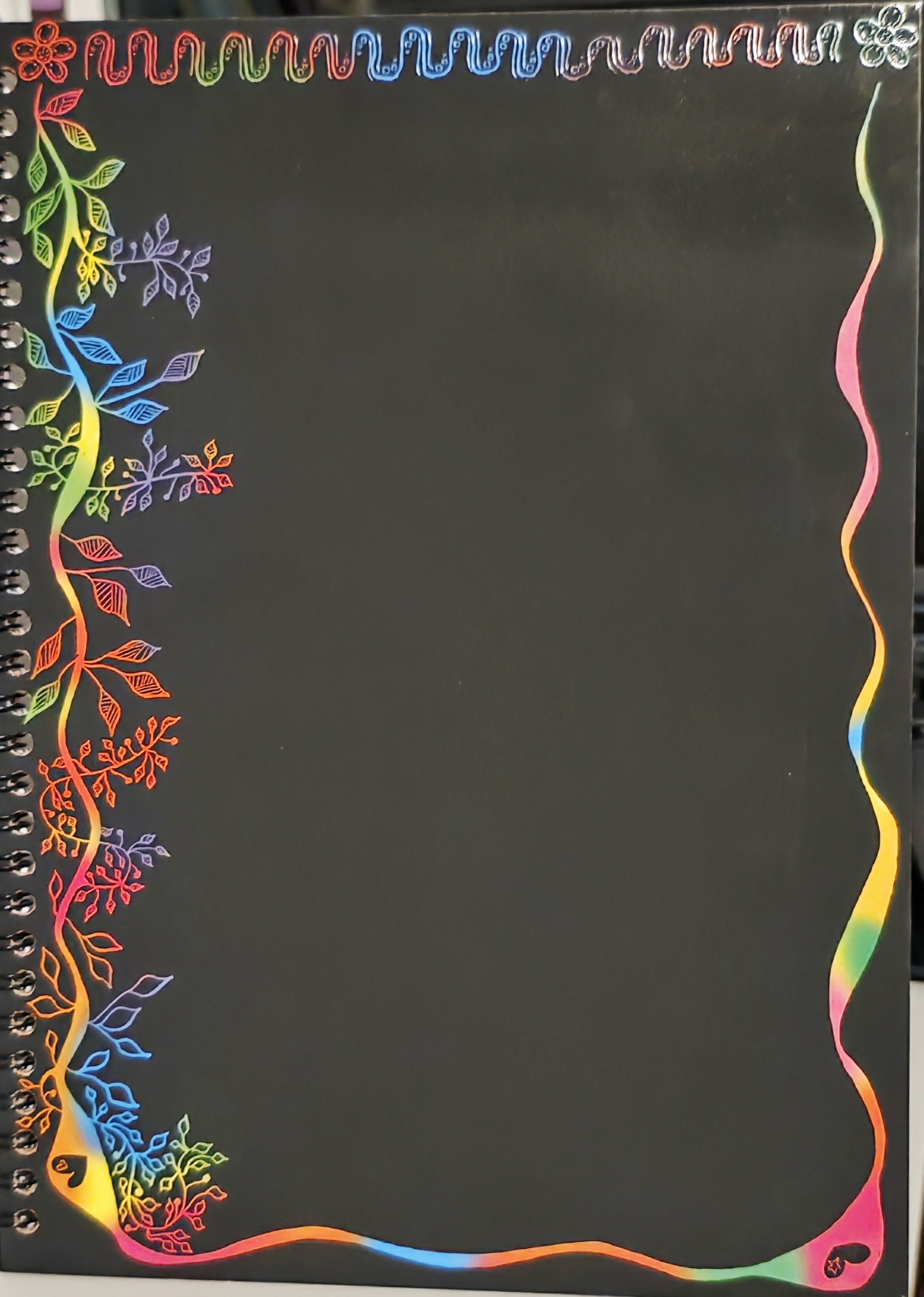 A scratch art work in progress showing flowers & vines with leaves.